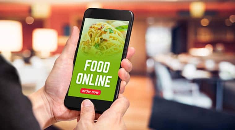 Close up hand holding mobile phone with order food online word on screen with blur restaurant bokeh light background,online food marketing concept